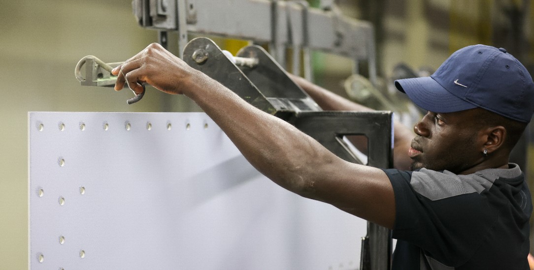 Abdoulle Bojang aus Gambia, Mitarbeiter der omeras GmbH, hängt Stahlbleche für die Oberflächenbehandlung an ein Transportband. In Sachsen gehen mehr Fachkräfte in den Ruhestand als junge Menschen ins Arbeitsleben starten. Deswegen braucht es nach Ansicht von Fachleuten mehr Arbeits- und Fachkräfte aus dem Ausland. Deren Anteil hat sich laut Regionaldirektion der Bundesagentur für Arbeit seit 2013 mehr als vervierfacht von 1,8 auf 7,4 Prozent. Bundesweit liegt der Anteil allerdings etwa doppelt so hoch. Wirtschaftsminister Dulig (SPD) informiert sich am selben Tag in mehreren Unternehmen über ihre Erfahrungen mit internationalen Teams.