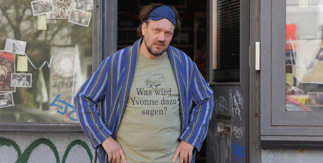 Zu schön, um wahr zu sein: Micha (Charly Hübner) soll einst eine Massenflucht aus der DDR ermöglicht haben. Der zerzauste Berliner Videothekenbesitzer wird plötzlich zum Medienstar.(Foto: © Frederic Batier / X-Filme AG via Filmstarts.de)