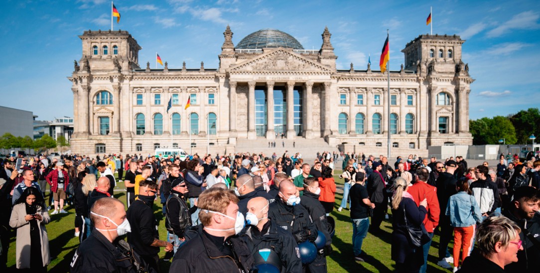 Polizeibeamte mit Mund-Nasen-Schutz in einer Menschenmenge vor dem Reichstagsgebäude. (Foto: pa/Nietfeld)