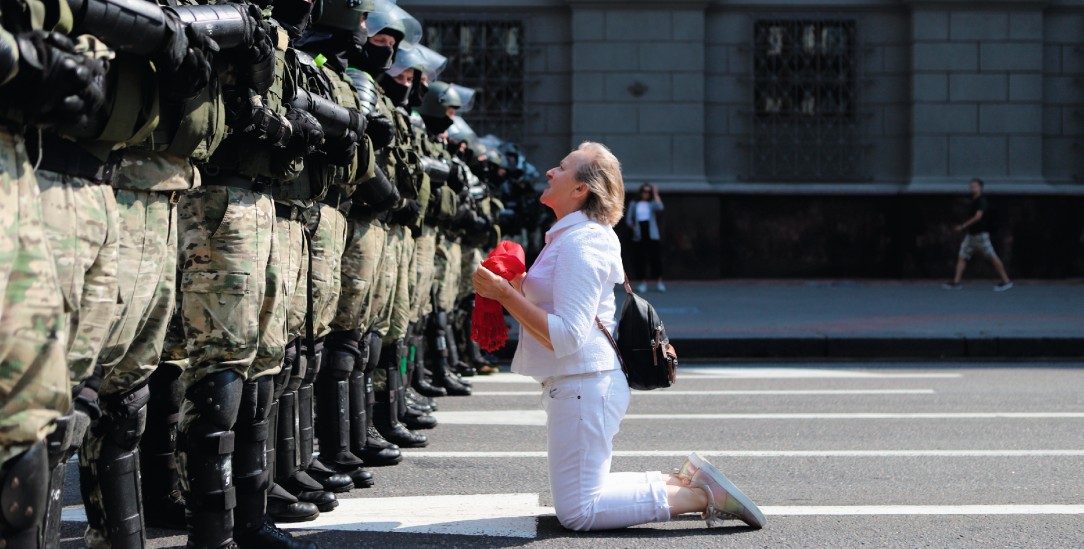 Innere Stärke: Allein und auf Knien protestiert diese Frau in Minsk gegen martialisch ausgestattete Polizisten (Foto: pa/ap)