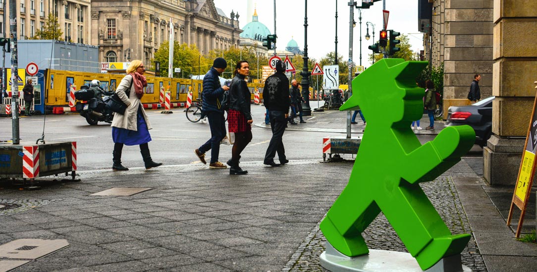 Nicht überall ist so viel Platz: Fußgänger und grünes Ampelmännchen auf einem Bürgersteig in Berlin (Foto: iStock by Getty/Avunchik)
