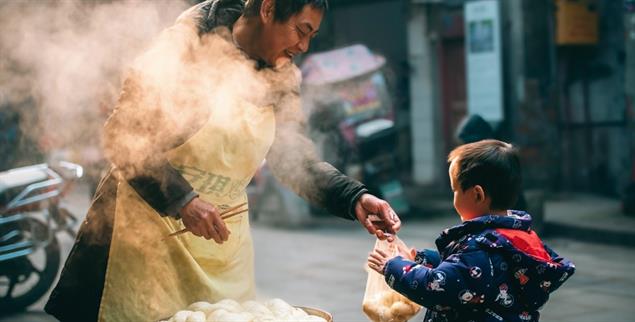 Der Geschmack von Heimat: Ein Straßenverkäufer überreicht einem Jungen eine Tüte voller Mantou, so heißen diese Dampfbrötchen in China. (Foto: Li Zhang/World Food Photography Awards sponsored by Bimi®)