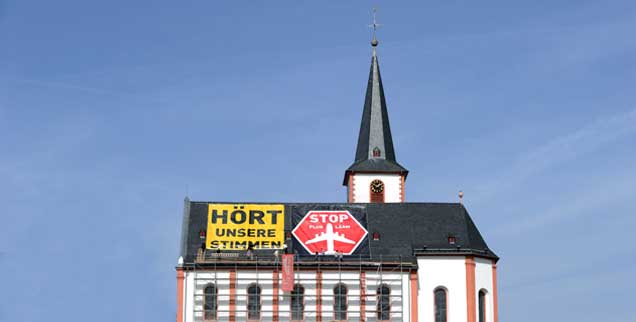 Der Protest gegen den Fluglärm ist in der Rhein-Main-Region immer öfter auch aus der Luft zu sehen: Hier wehrt sich die katholische St. Peter und Paul-Gemeinde Hochheim mit starken Worten auf ihrem Kirchendach. (Foto: pa/Dedert)
