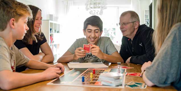 Gesellschaftspiel mit Familienanschluss: Abdulkarim (Mitte) aus Syrien lebt in Bremen bei Pflegefamilie Wilken. Er ist einer von Tausenden unbegleiteten minderjährigen Flüchtlingen in Deutschland. (Foto: epd/ Michalak)