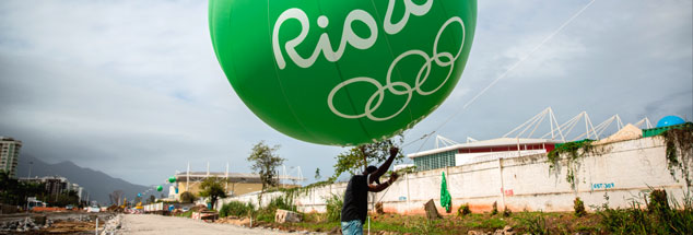 Hier steht heute ein Olympia-Stadion: Ein Arbeiter hält im August 2014 einen grünen Ballon mit der Aufschrift »Rio 2016« hoch. Im August 2016 sieht es an dieser Stelle ganz anders aus. (Foto: pa/dpa/Michael Kappeler)