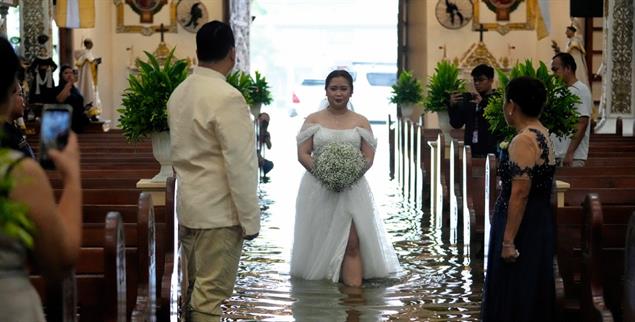 Bride Jamaica Agular walks down the aisle during her wedding at the flooded Barasoain church in Malolos, Bulacan province, Philippines on Tuesday, July 22, 2025. (AP Photo/Aaron Favila)