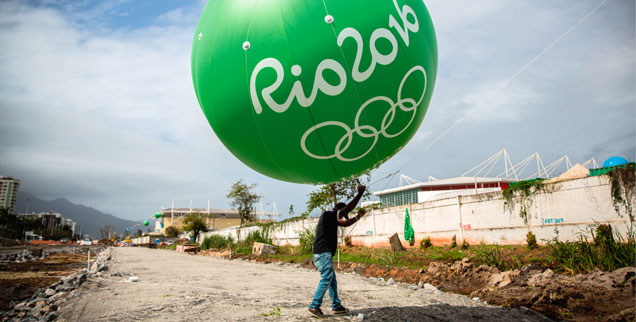 Hier steht heute ein Olympia-Stadion: Ein Arbeiter hält im August 2014 einen grünen Ballon mit der Aufschrift »Rio 2016« hoch. Im August 2016 sieht es an dieser Stelle ganz anders aus. (Foto: pa/dpa/Michael Kappeler)