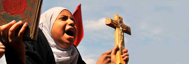 Mit Koran und Kreuz auf der Straße: Eine junge Frau demonstriert in Kairo gemeinsam mit Hunderten von Menschen gegen Konfessionalismus und Feindschaft unter den Religionen. (Foto: pa/upi/Hosam /landov)