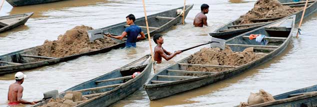 Der Abbau ist in Indien harte Arbeit: Männer stehen bis zum Bauch im Wasser und schaufeln aus dem Kulsi-Fluss Sand in ihre Boote (Foto: pa/epa)