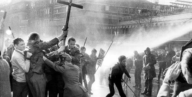 14. April 1968, Berlin, Demonstranten mit Kreuzen im Strahl der Wasserwerfer: Nach dem Anschlag auf Rudi Dutschke halten die öffentlichen Proteste an. Bei dieser Demo am Ostersonntag sind es über 2500 Ostermarschierer und Angehörige der außerparlamentarischen Opposition, die mehr Demokratie und einen grundlegenden Wandel der Gesellschaft  fordern. (Foto: pa/Giehr)
