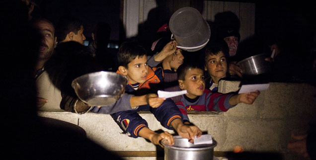Syrische Flüchtlinge, darunter zahlreiche Kinder, warten auf die Essensausgabe in einem Lager im Grenzgebiet zwischen der Türkei und Syrien: Die Lebensbedingungen in den Camps sind oft schwierig. Nun ist zu erwarten, dass die Versorgung nicht mehr aufrecht erhalten werden kann wie bislang. (Foto: pa/dpa/Maysun) 