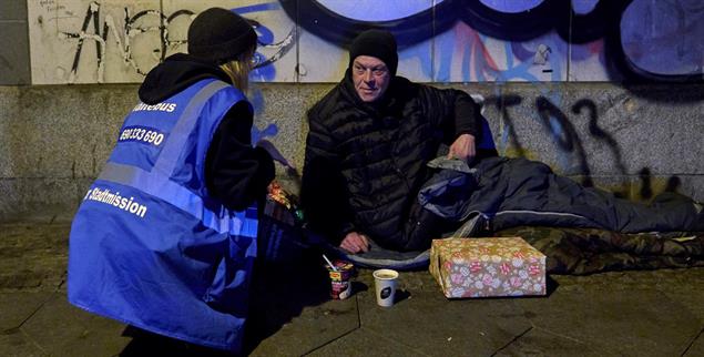Die Zivilgesellschaft springt ein: Eine Ehrenamtliche der Berliner Stadtmission versorgt einen Obdachlosen am Ostbahnhof. (Foto: PA/epd-Bild/Christian Ditsch)