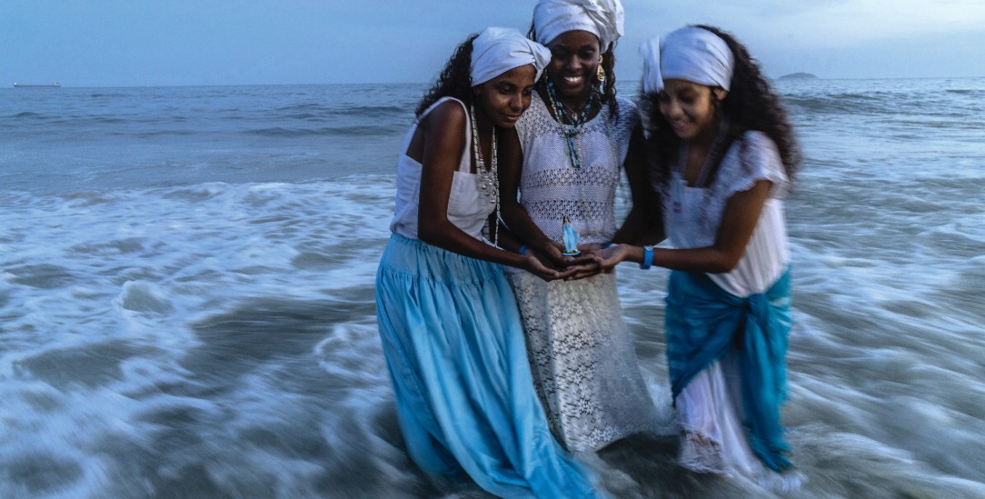 Ein heiliger Moment: Drei Frauen, Angehörige der Umbanda-Religion, opfern am Jahreswechsel Blumen. Weil die Copacabana in Rio de Janeiro von Silvesterfeiernden überfüllt ist, suchen sie für ihr Ritual abgelegenere Strände auf. (Foto: laif/The New York Times/Redux)