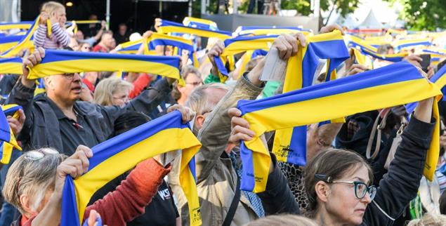 Teilnehmende des Katholikentags in Stuttgart halten Schals in den Nationalfarben der Ukraine in die Höhe (Foto: KNA/Harald Oppitz)