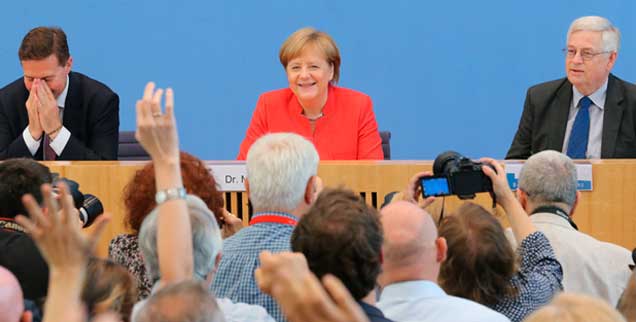 Bundespresskonferenz, heute Mittag, ernste und amüsante Fragen von Journalisten: Auf dem Podium eine urlaubsreife Kanzlerin, umrahmt von Regierungssprecher Steffen Seibert (links) und dem Vorsitzenden der Konferenz, Gregor Mayn. tz(Foto: pa/Kumm)
