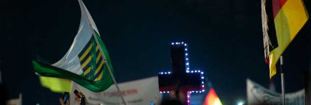 Das Kreuz, ein nationales Symbol? Für rechte Christen ist es das offensichtlich. Wie hier bei einer Demonstration der Pegida-Bewegung. (Foto: pa/Burgi)