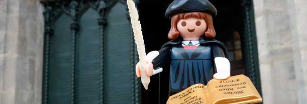 Playmobil-Luther vor der Thesentür an der Schlosskirche in Wittenberg: Am 31. Oktober 1517 soll der echte Reformator seine 95 Thesen hier  eigenhändig an die Tür genagelt haben. (Foto. pa/Kasper/FSU)

