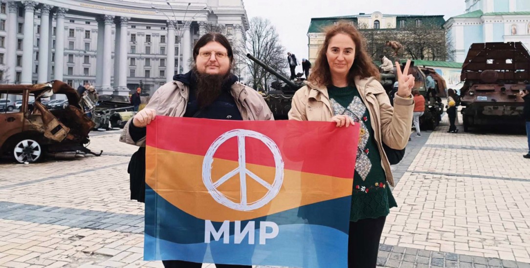Make Peace Not War: Scheljaschenko und Alexia Tsouni auf dem Michaelplatz in Kiew. Hinter ihnen stehen zerstörte russische Panzer aus dem laufenden Krieg. Sie sind Teil einer Dauerausstellung. (Foto: privat)