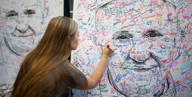 Franziskus als Projektionsfläche: Eine Studentin aus Minnesota unterschreibt auf einem Papstposter für Reformwünsche. (Foto: Reuters/Mark Makela)