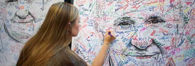 Franziskus als Projektionsfläche: Eine Studentin aus Minnesota unterschreibt auf einem Papstposter für Reformwünsche. (Foto: Reuters/Mark Makela)