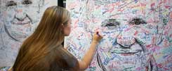 Franziskus als Projektionsfläche: Eine Studentin aus Minnesota unterschreibt auf einem Papstposter für Reformwünsche. (Foto: Reuters/Mark Makela)