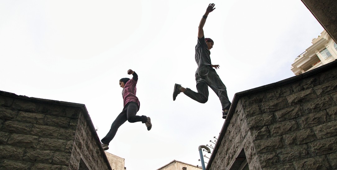 Hindernisse überwinden: Fatemeh Akrami (links im Bild) ist Parkour-Läuferin. Sie rennt, springt und balanciert in Parks und anderswo. Außerdem ist sie die erste Frau, die in Iran Fallschirmspringen ausprobiert – deshalb wird sie auch das Vogelmädchen genannt. Ihr eigenes Geld verdient sie als Gymnastik- und Fitnesstrainerin für Mädchen in Teheran. (Foto: Samaneh Khosravi/Kerber Verlag)